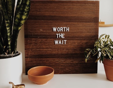 white Worth The Wait sign on brown wooden board