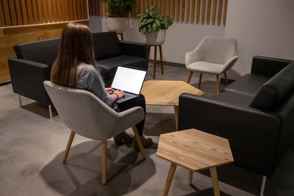 woman sitting on chair and using laptop