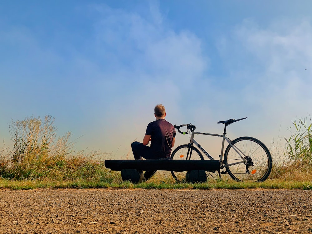 白い自転車の近くに座っている男性