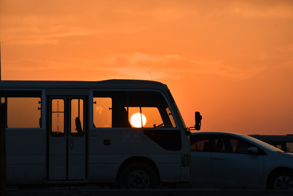 white bus beside sedan at golden hour