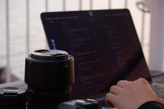 black telephoto lens beside laptop computer