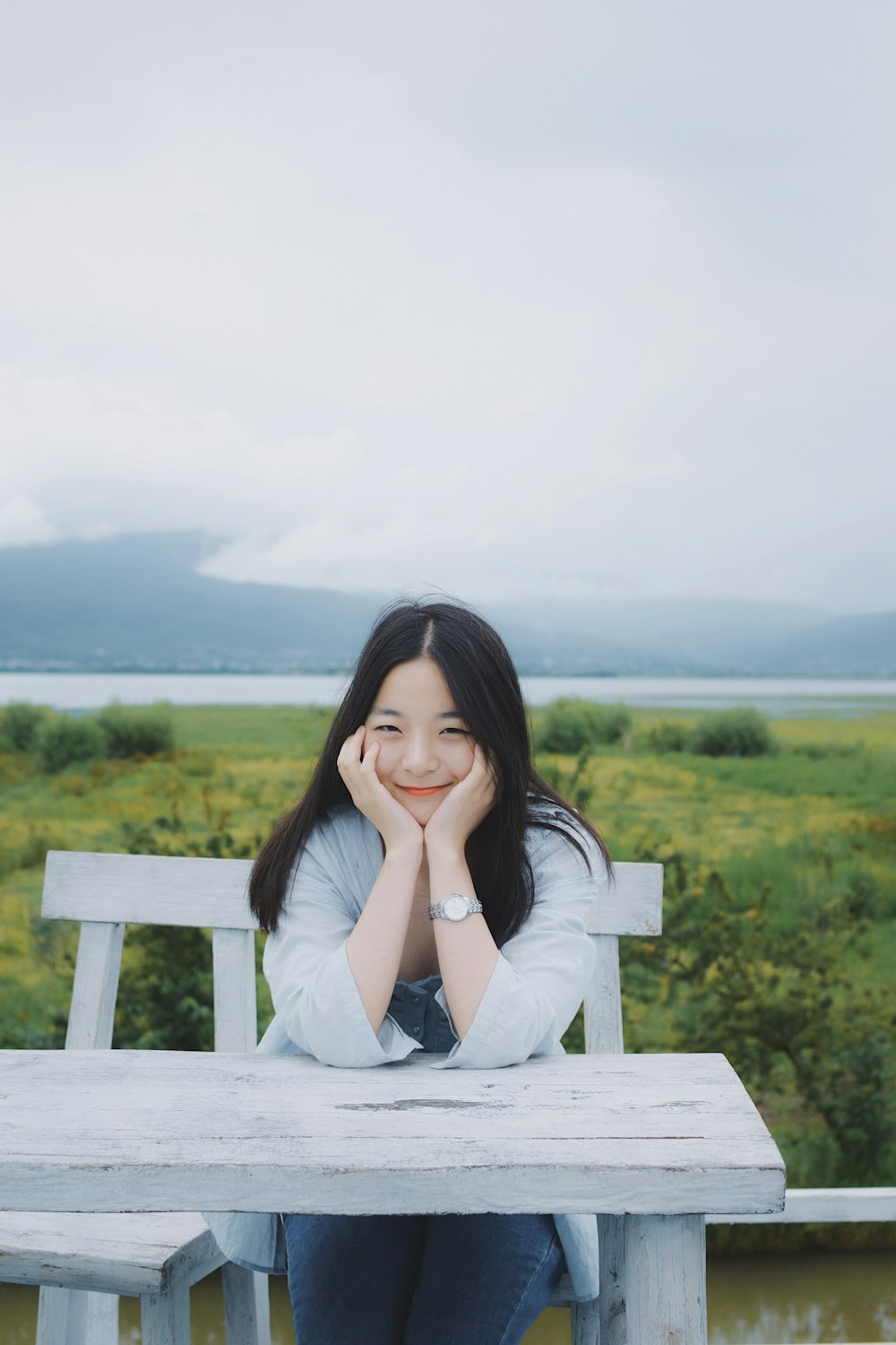 woman placing hands on cheeks while sitting on bench