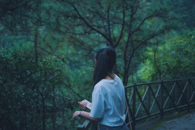 woman leaning on wooden railing overlooking trees