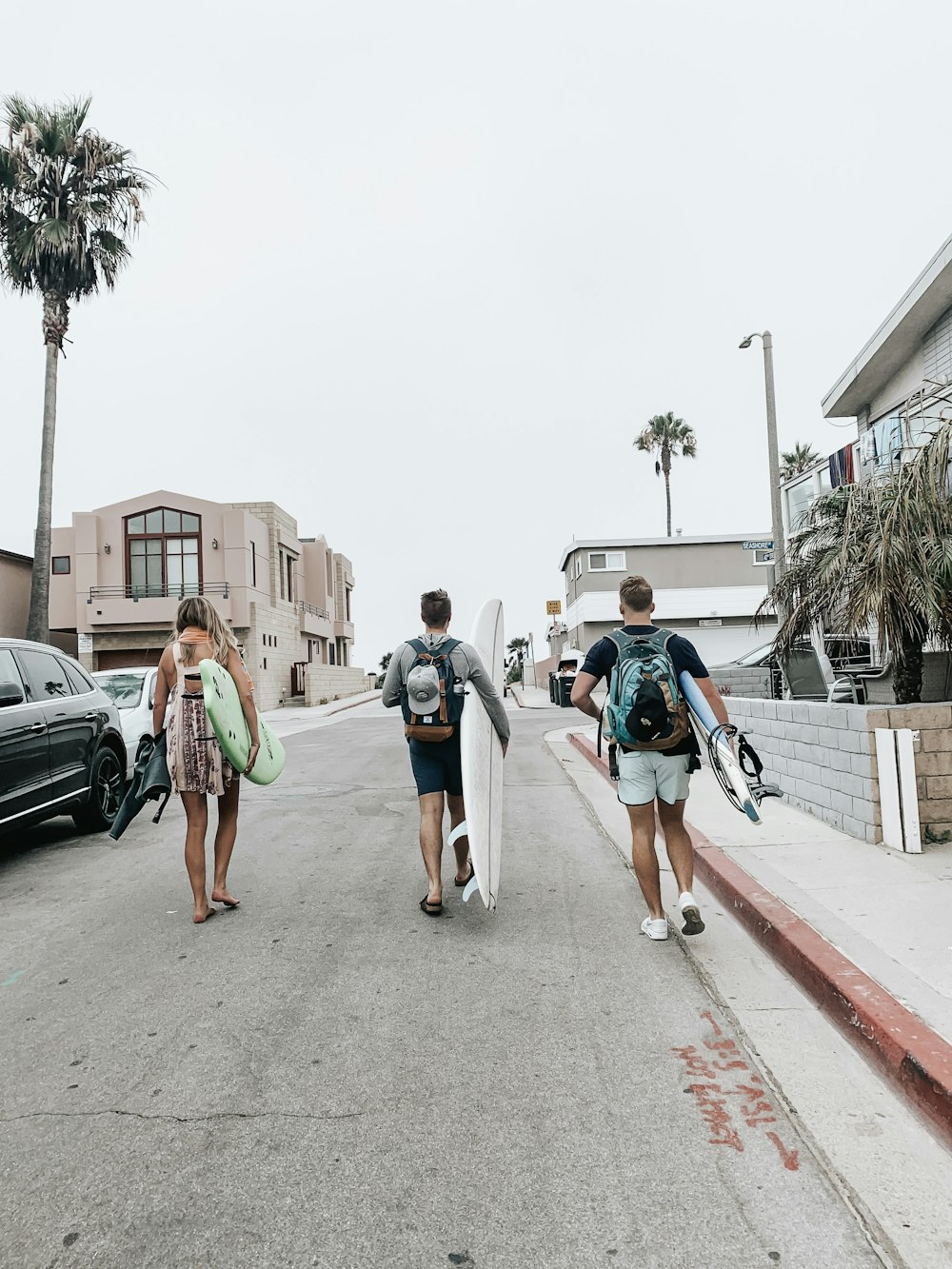 three person carrying surfboards