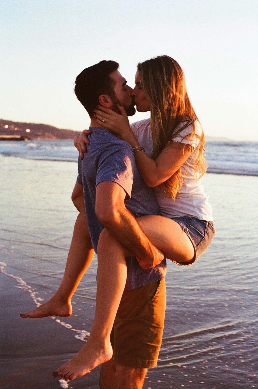 Mann trägt und küsst Frau am Strand