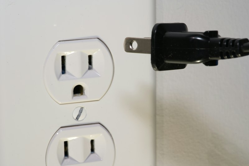 A plug held up to a wall socket, about to connect