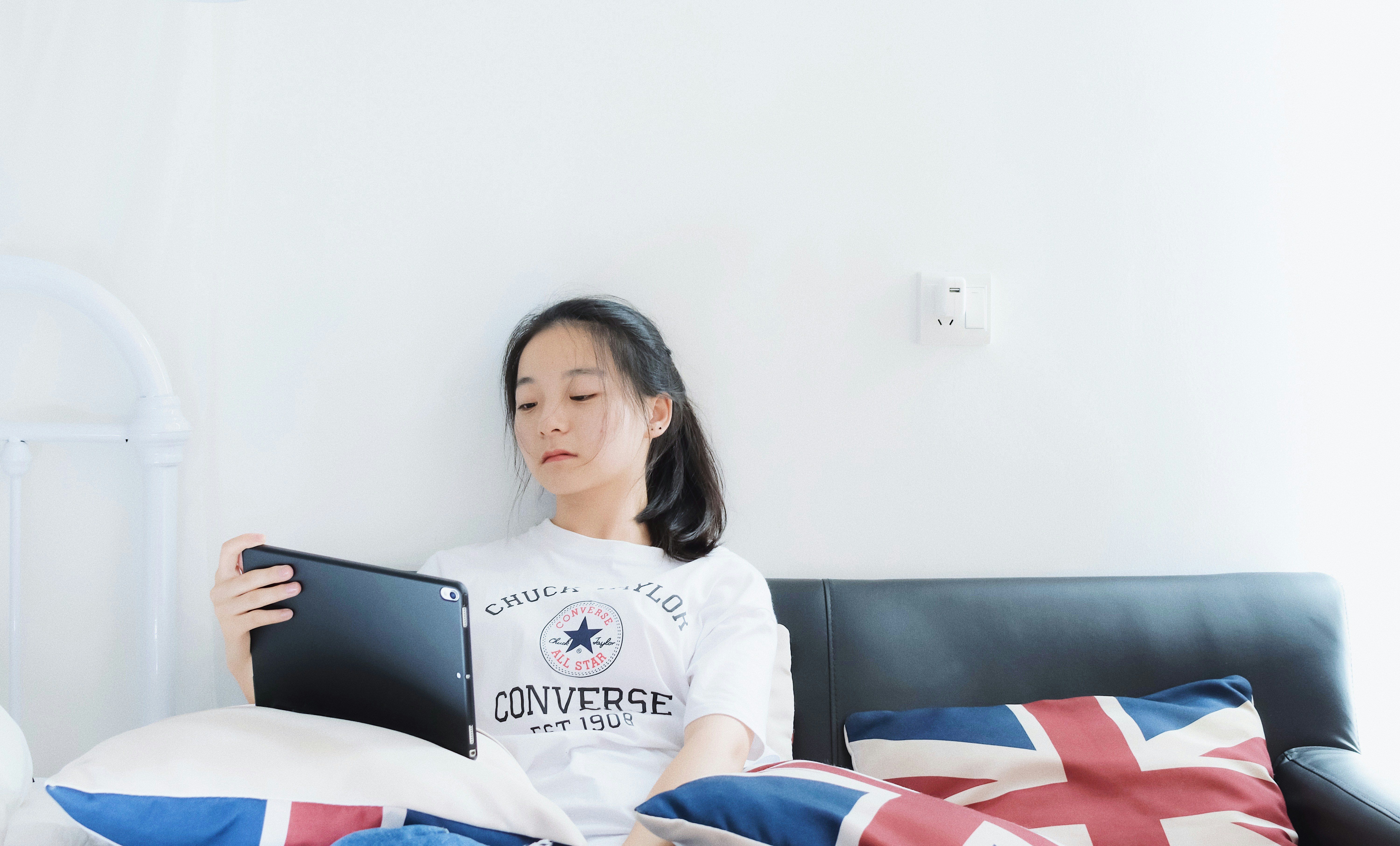 women sitting in a sofa holding a tablet close-up photography
