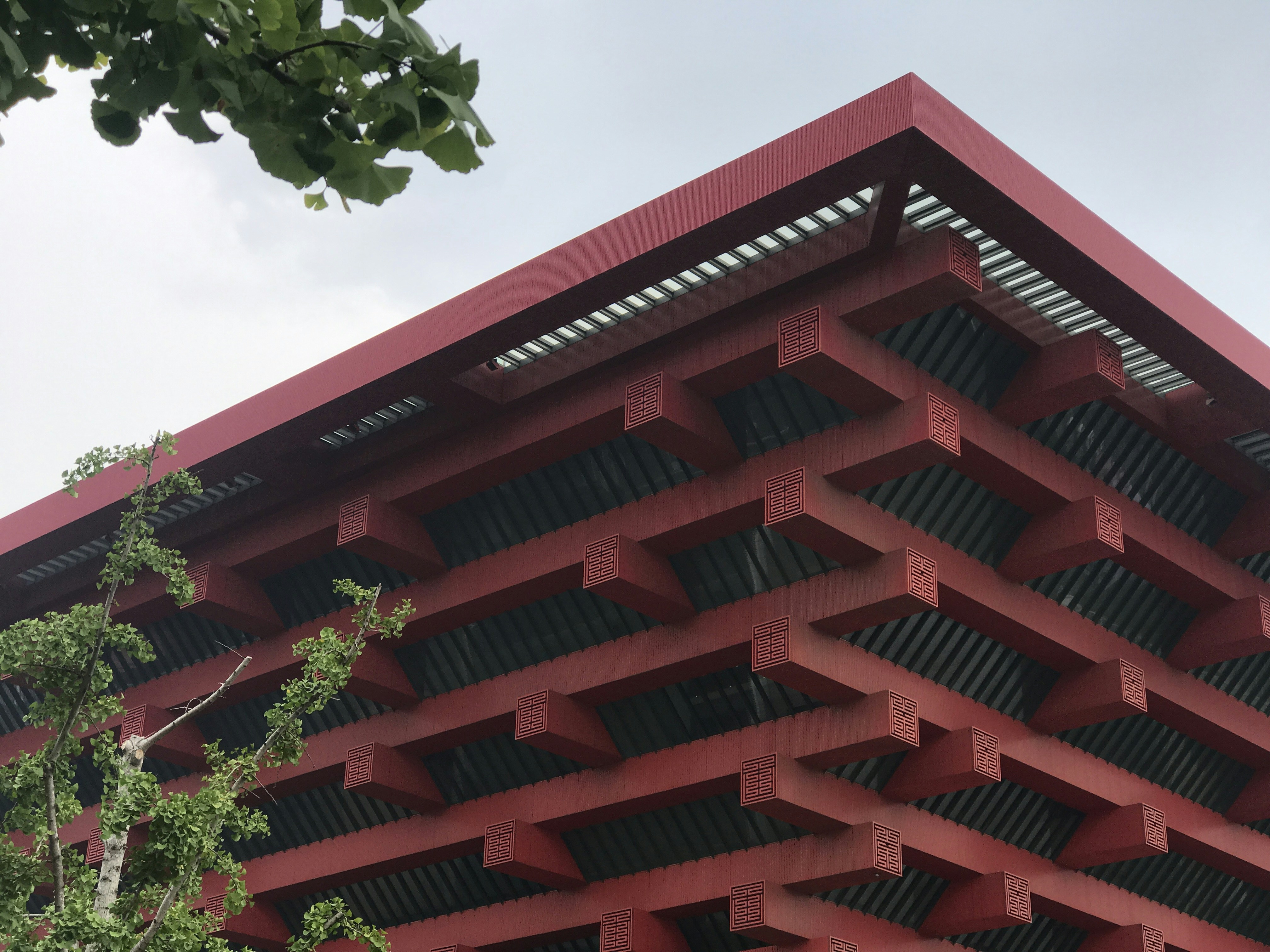 緑の木の横の赤い建物の写真