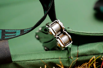 Close-up of a deep crimson leather belt with intricate stitching against a matte forest green fabric background.