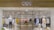 A clothing store display featuring mannequins dressed in casual attire, such as striped and checked shirts and skirts. The store interior is organized with neatly arranged racks of various clothing items, including shirts, blouses, and jackets in a range of colors such as yellow, white, pink, black, and blue. The entrance has glass doors, and the store name is prominently displayed above in bold letters. The lighting is bright, highlighting the clean, modern aesthetic of the space.