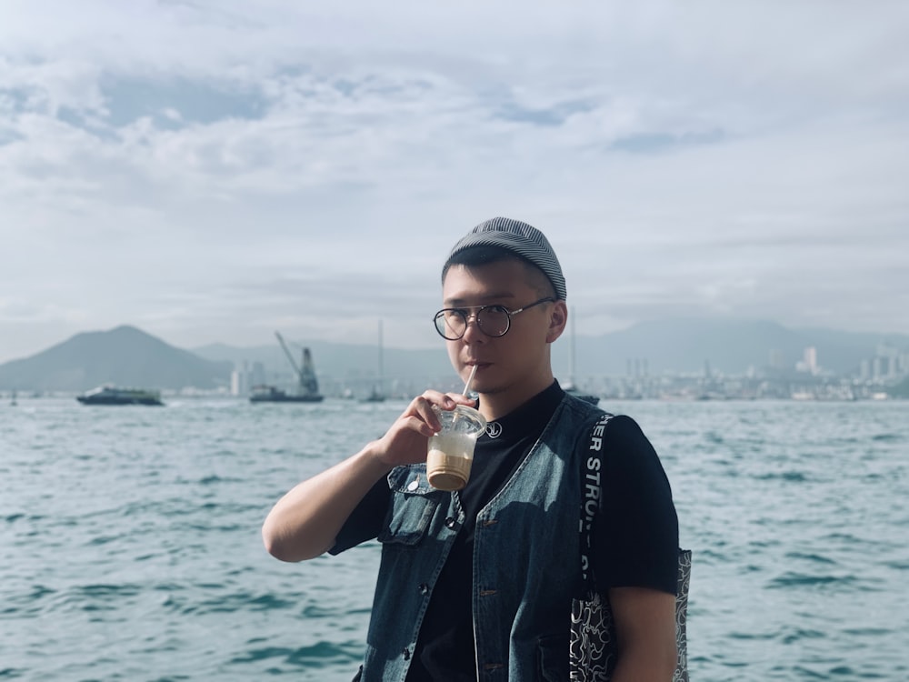 man holding cup near body of water