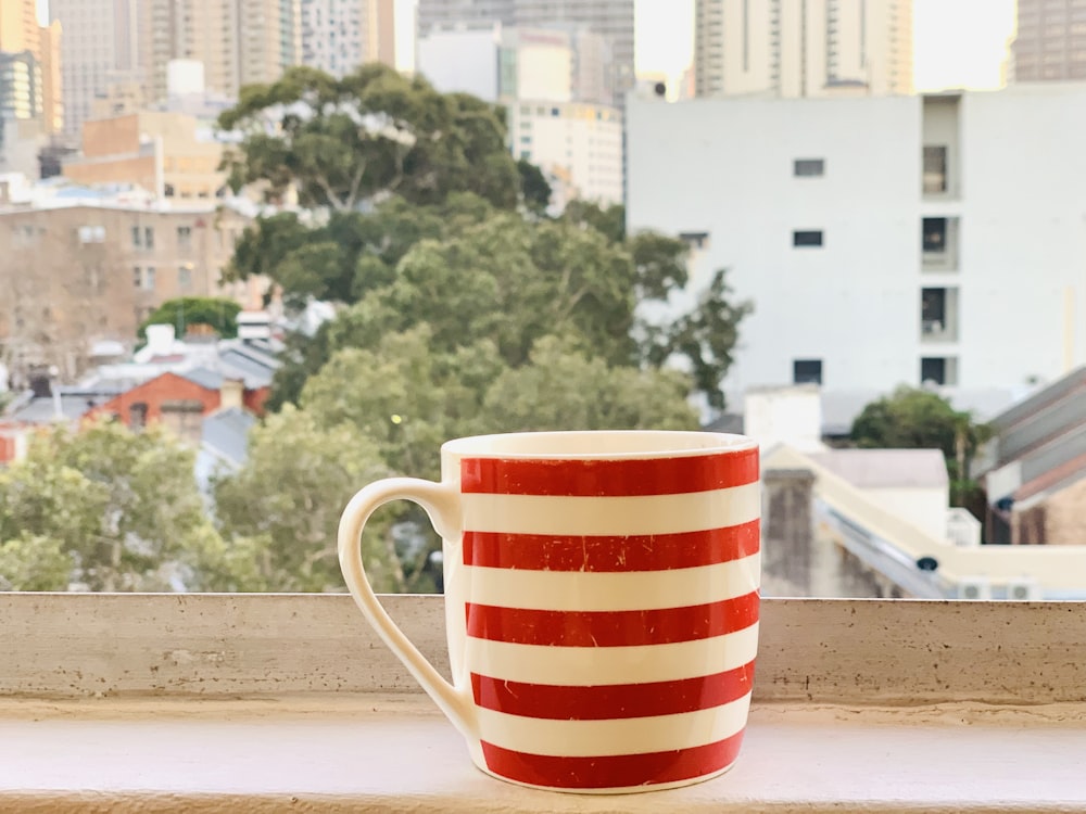 red and white stripe ceramic mug across trees and buildings