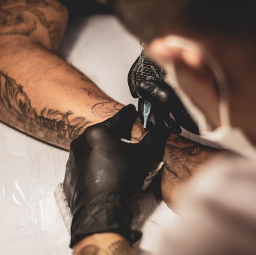 shallow focus photo of person tattooing person's right arm