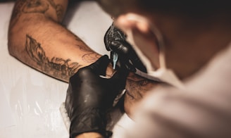 photo of best tattoo artist tattooing in shop near fine line arm tattoo