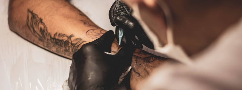 photo of best tattoo artist tattooing in shop near fine line arm tattoo