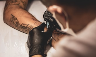 shallow focus photo of person tattooing person's right arm