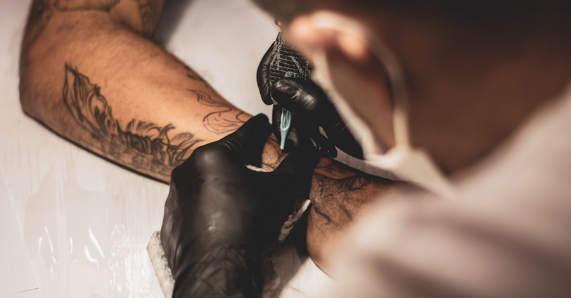 shallow focus photo of person tattooing person's right arm