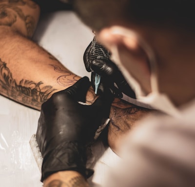 shallow focus photo of person tattooing person's right arm