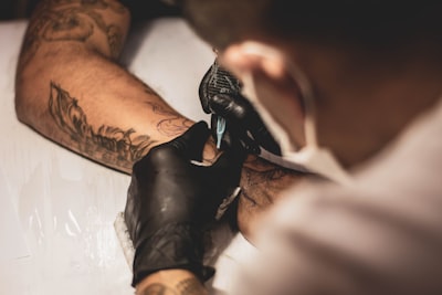 shallow focus photo of person tattooing person's right arm tattoo google meet background