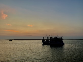 A serene view of a fishing boat on calm waters at sunset.
