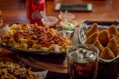 A colorful spread of munchies including fries, burgers, and dips under warm lighting.