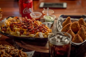 A platter featuring a variety of loaded fries with dinosaur-shaped dipping sauces in vibrant bowls.