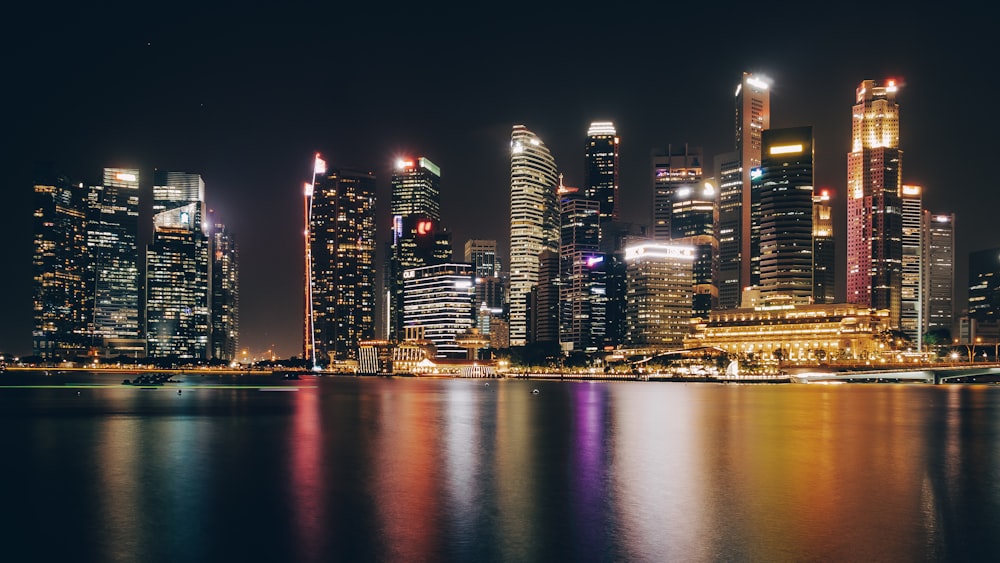 lighted city buildings near body of water during nighttime