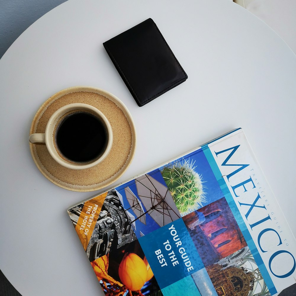 black wallet beside coffee filled mug on saucer