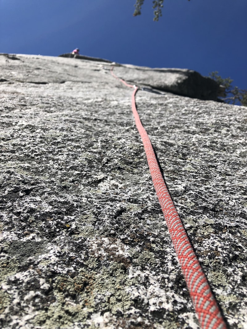 Vue plongeante depuis une falaise avec corde d'escalade colorée
