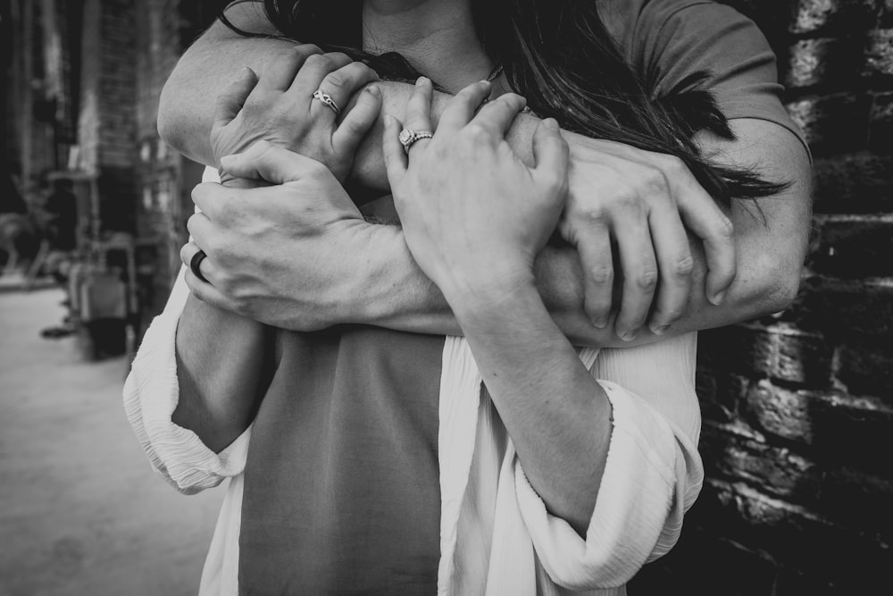 grayscale photo of man hugging woman
