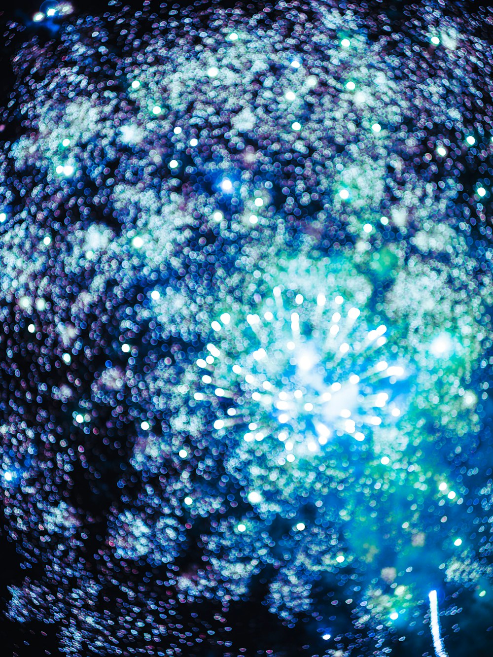 a blue and green firework in the night sky