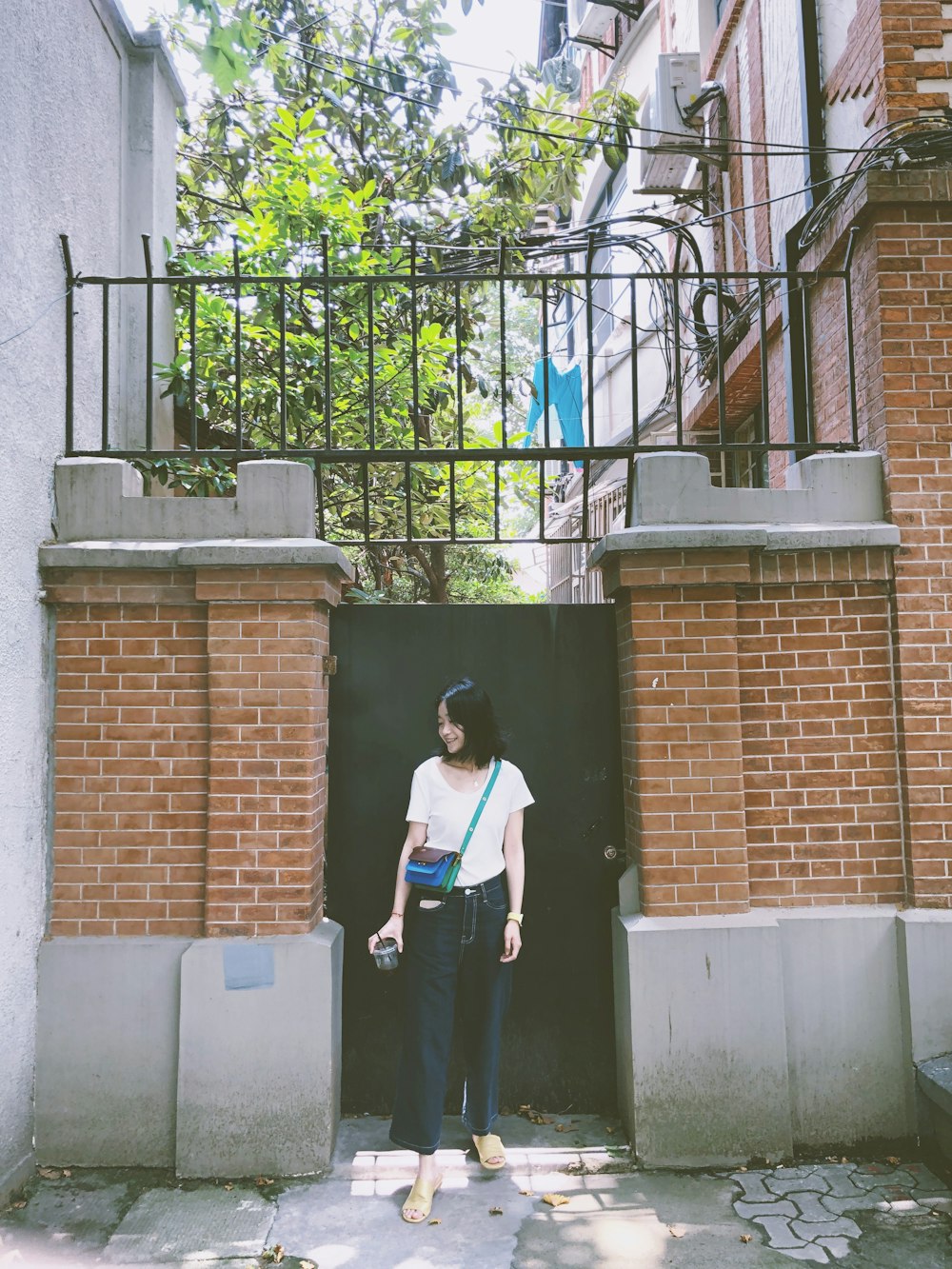 woman in white shirt and black pants standing near gate