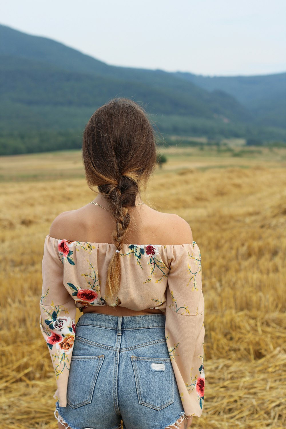 woman standing on grass field facing the mountains