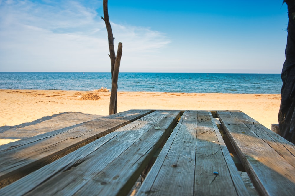 brown wooden dock viewing calm sea under blue and white skies