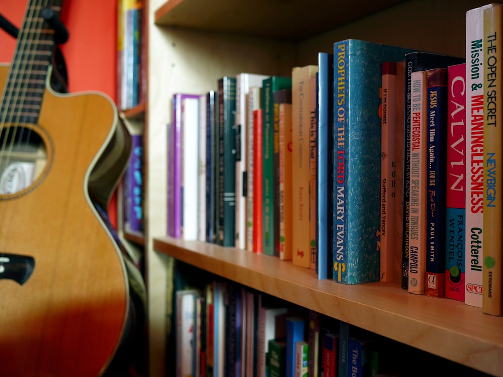brown guitar near book shelves close-up photography