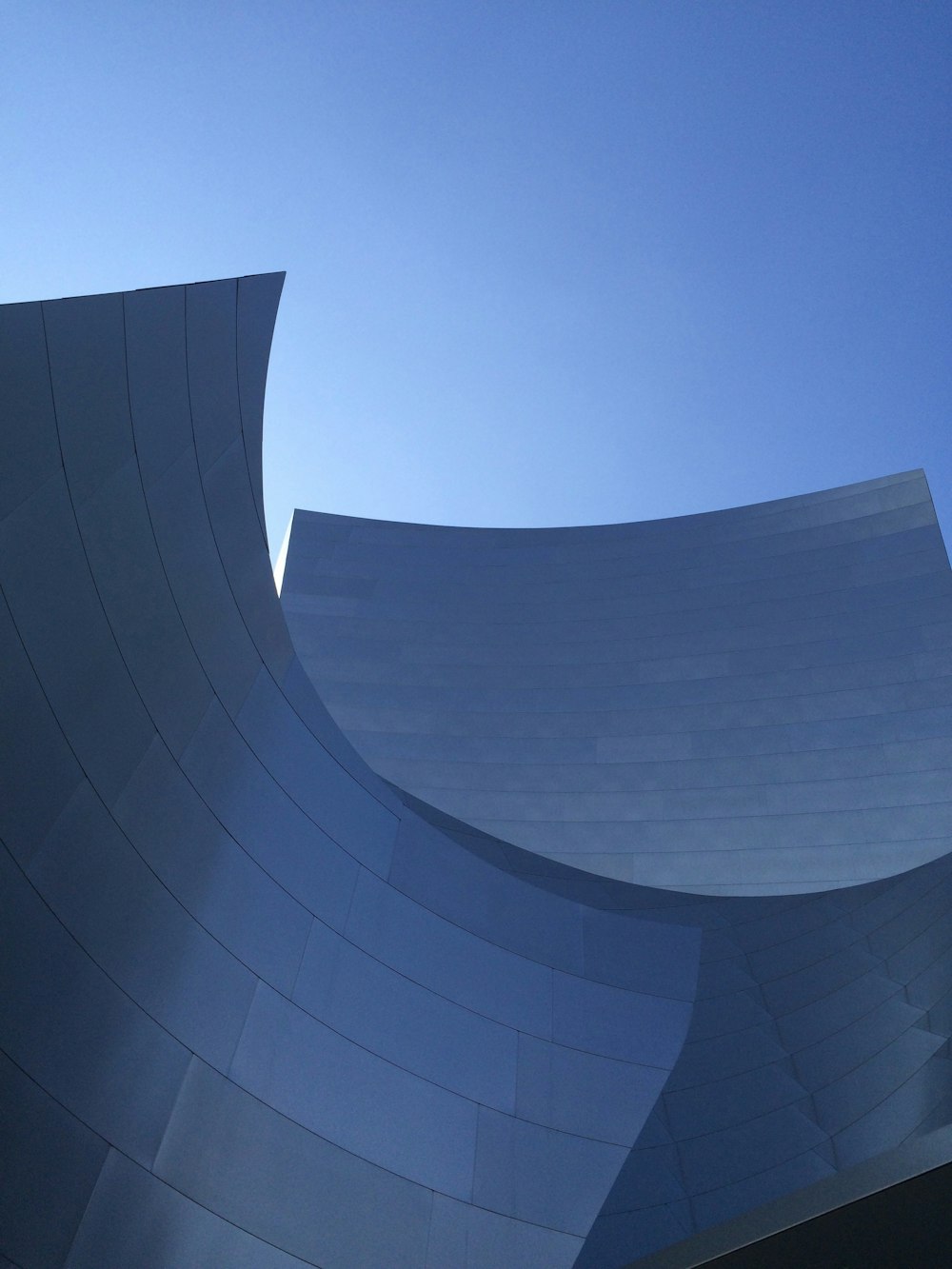 a building with a curved roof and a blue sky in the background