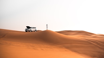 person standing beside silver SUV during daytime