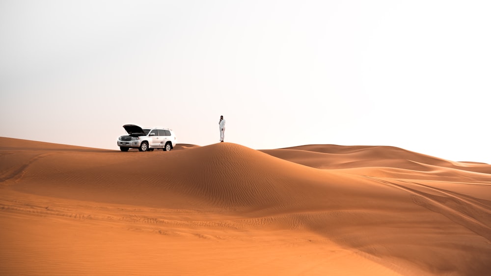 person standing beside silver SUV during daytime