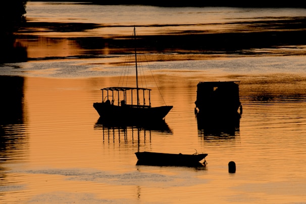 Sunset over the Rio Negro with boats gently floating near the shore.