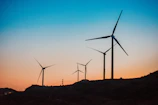 Wind turbines turning gently on a hillside at sunset