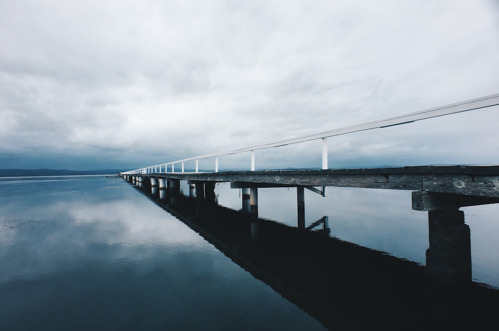 gray concrete bridge viewing blue sea under white skies