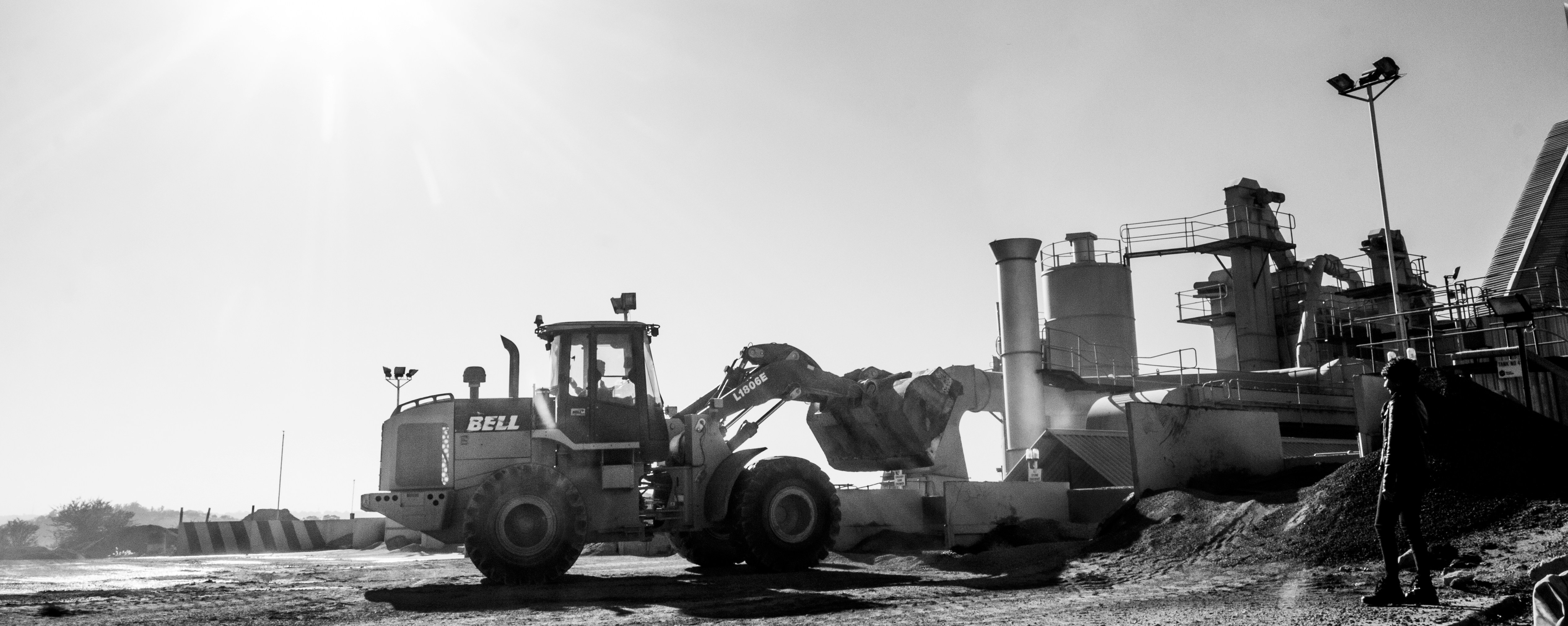 Bir iş makinesinin metal yüzeyindeki yoğun zift ve katran lekelerinin temizlenme aşamasını gösteren detaylı bir fotoğraf.