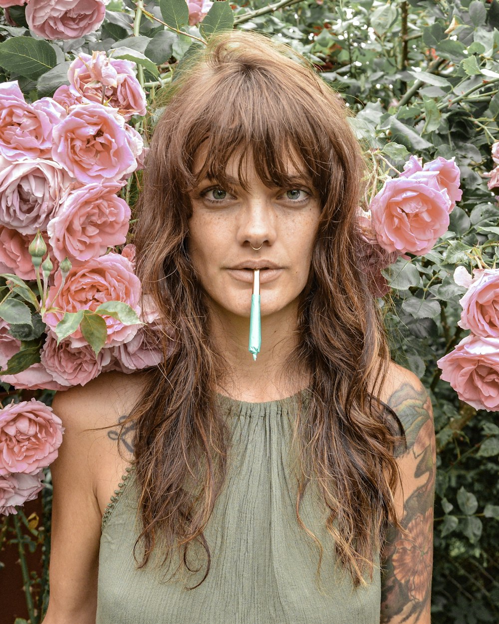 woman in green halter top standing by the pink roses