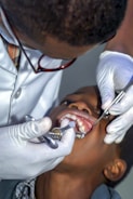 A dentist examining a child's teeth in a bright clinic.