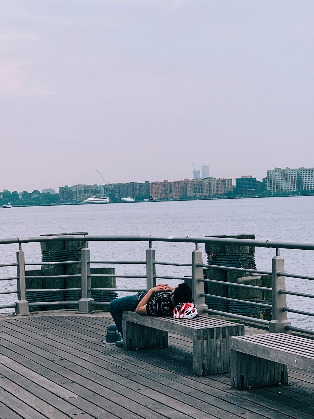 man in black striped shirt lying on bench beside rail