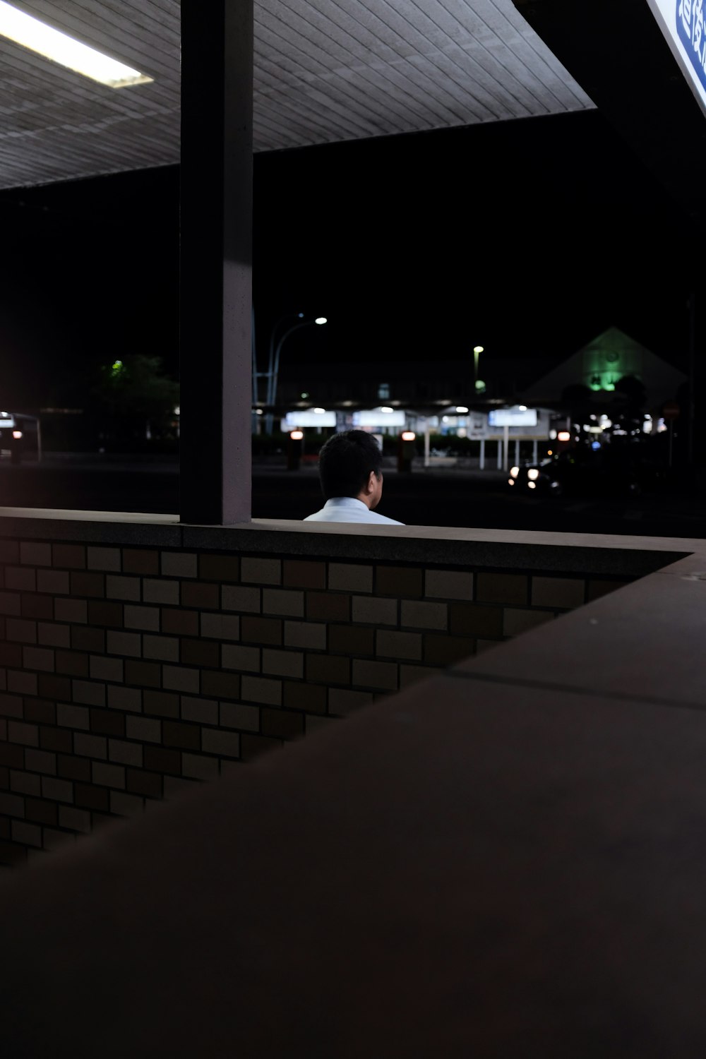 man in white shirt standing by the wall