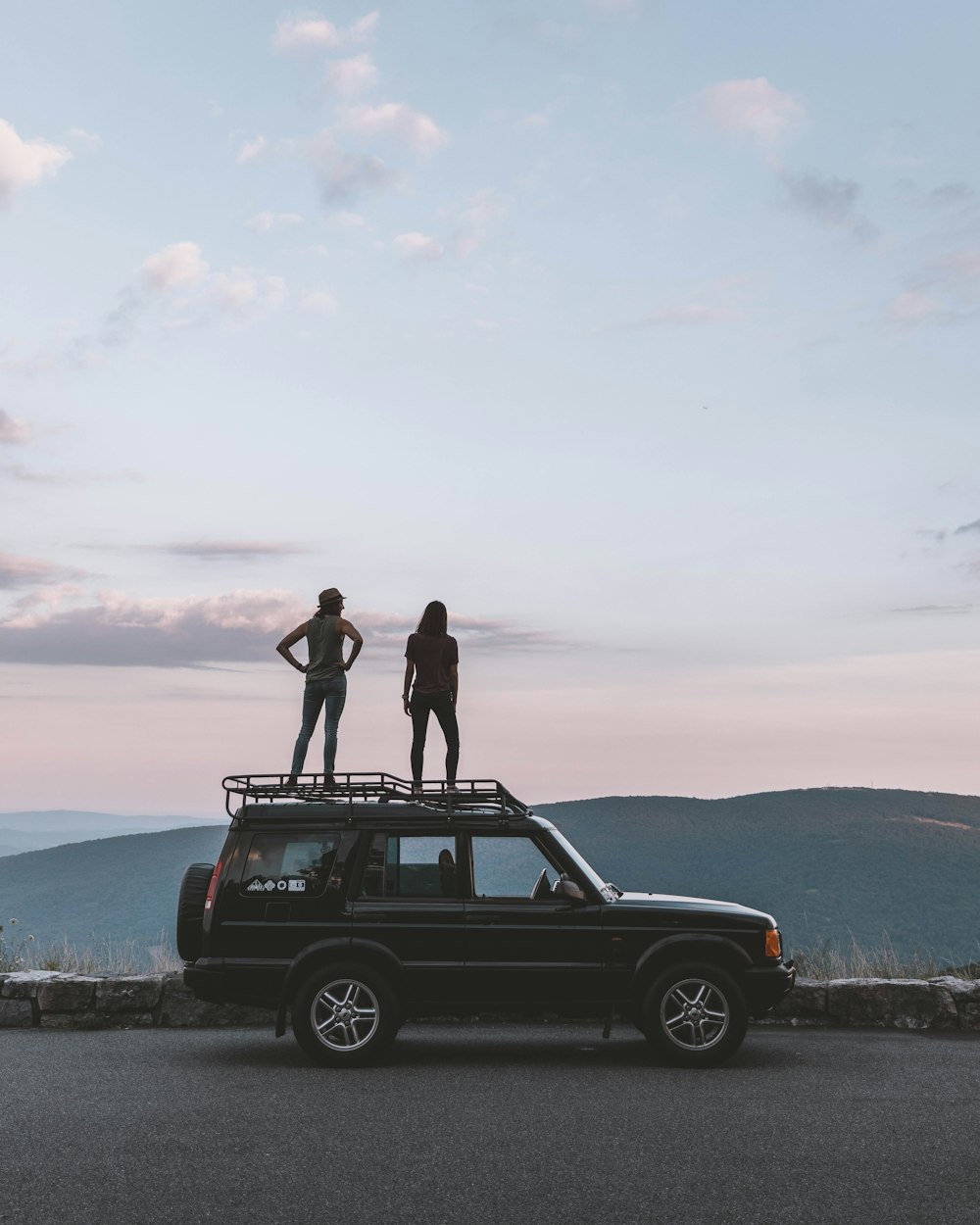 two women standing on car's roof