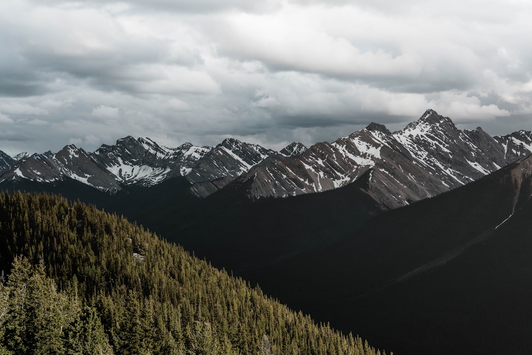 snow-capped gray rocky mountain under cloudy sky during daytime