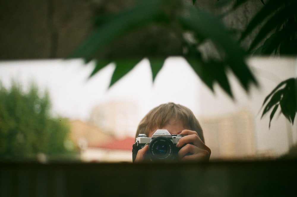 selective focus photography of person holding camera taking photo