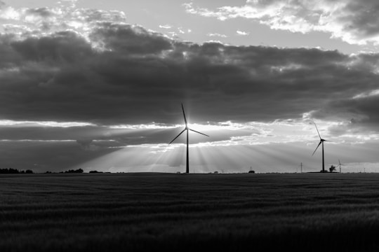 Close-up of sleek wind turbines turning against a dramatic sky, with solar panels reflecting golden light in the foreground.